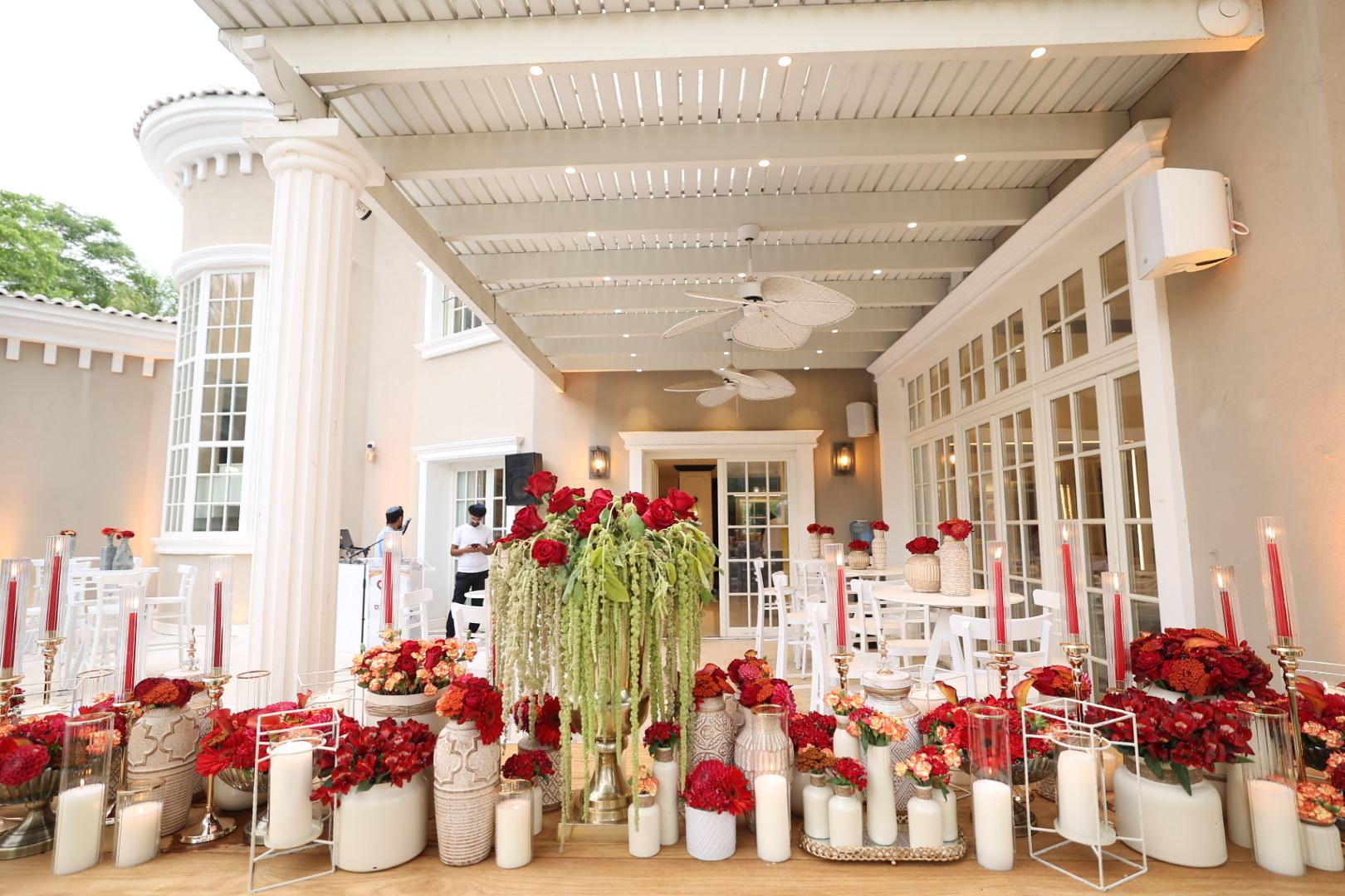 A white colonnade terrace dressed with red flowers and candles